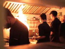 Cucina di un ristorante: i cuochi al lavoro davanti alla fiamma